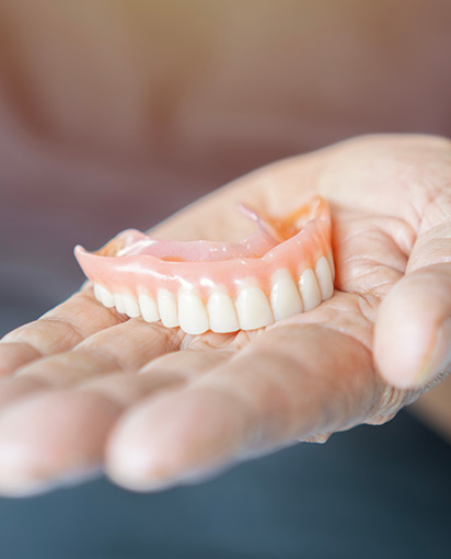 Man holding removable dentures in hand